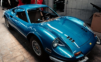Los Angeles luxury auto body shop: Blue Dino 206 GT vintage car, classic design, in a repair facility, automotive restoration focus.