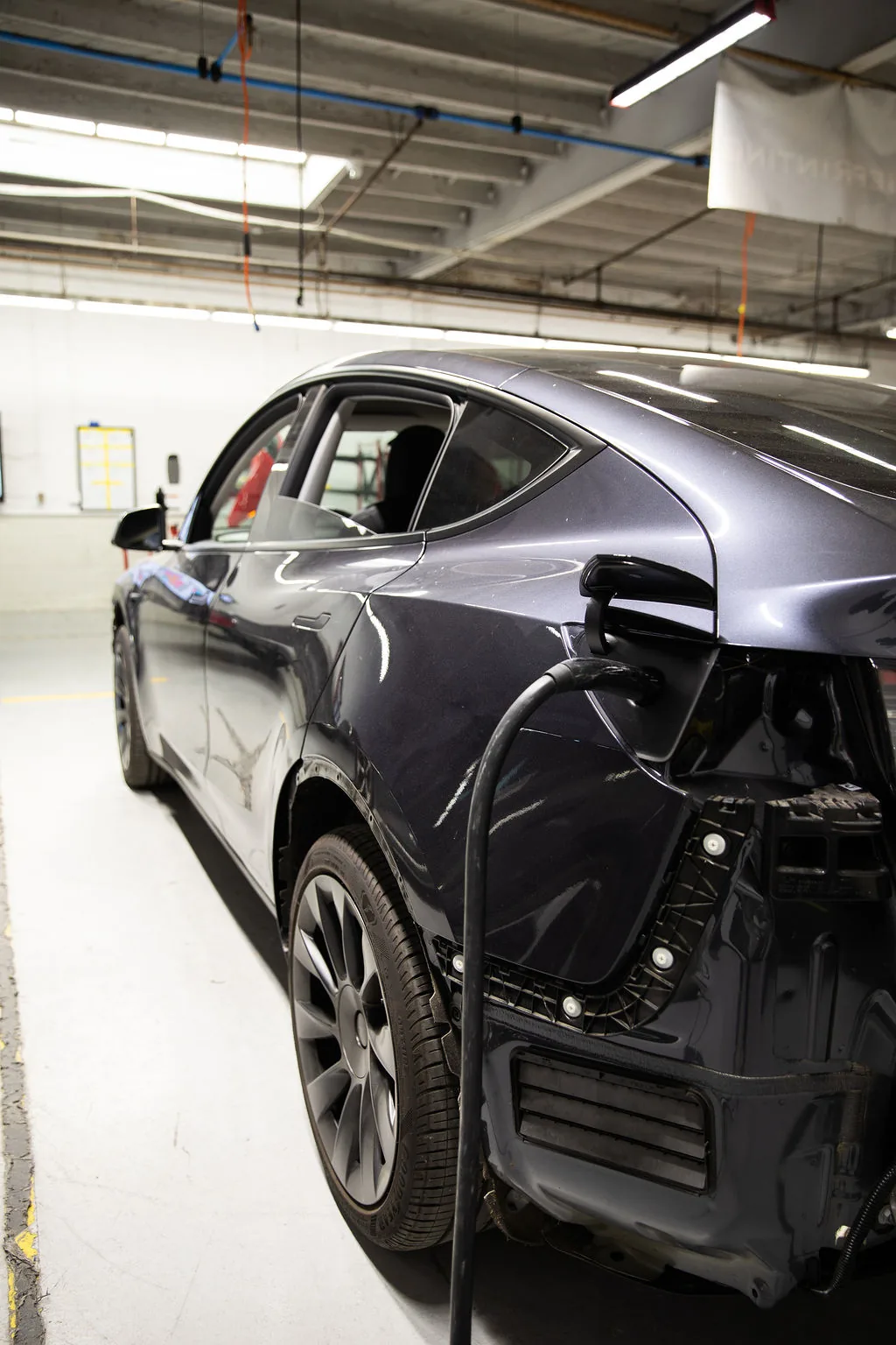 Tesla Model Y with rear quarter panel damage being repaired at a Los Angeles body shop before lease return