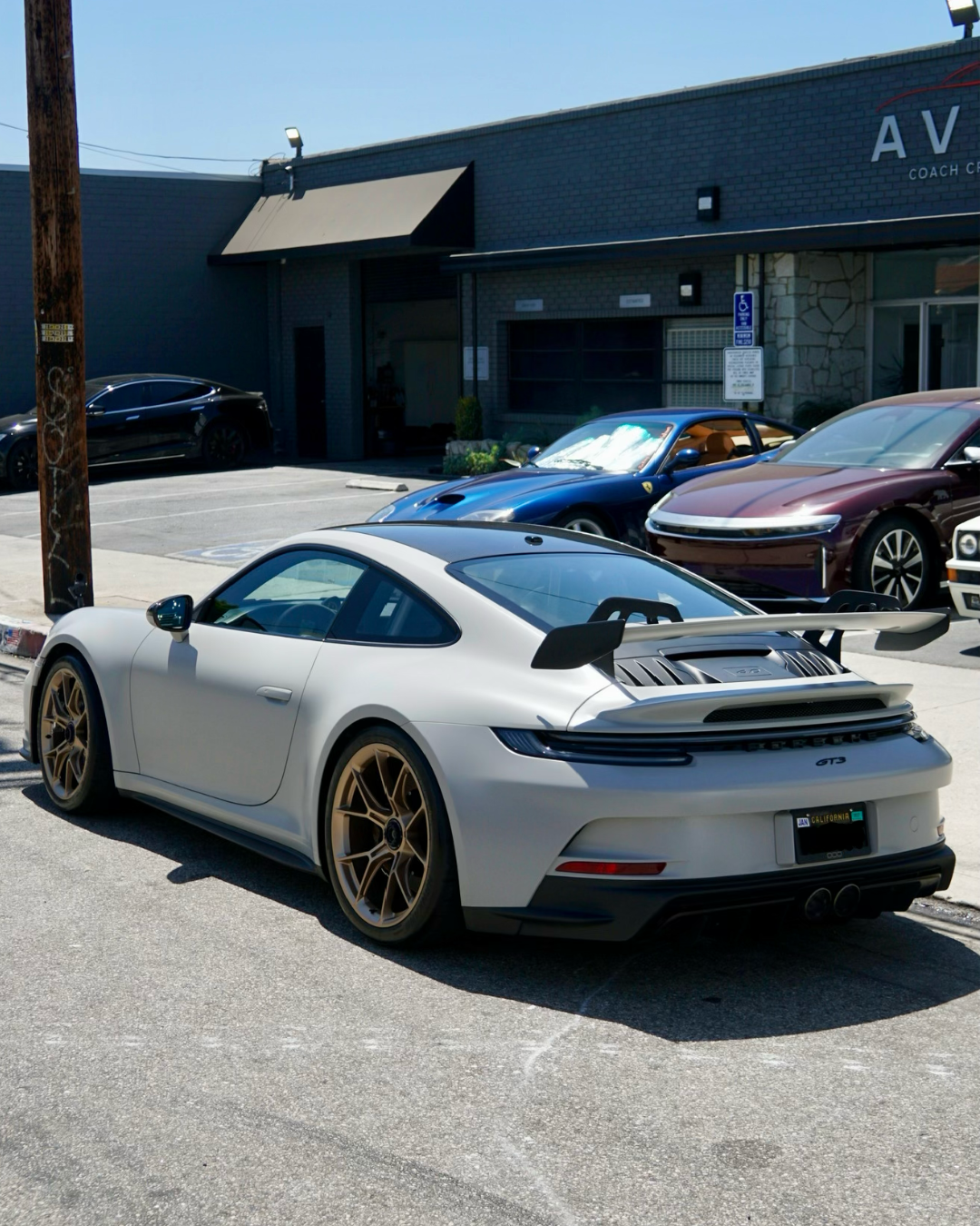 Red Ferrari 458 parked outside the Avio Coach Craft exotic collision repair shop in Los Angeles